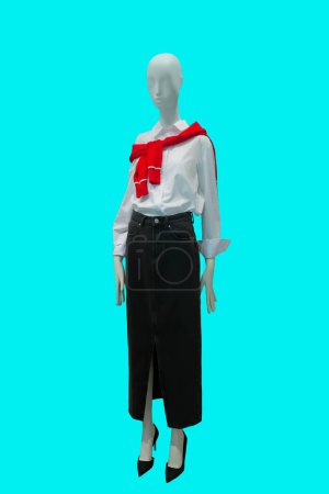 Full length image of a female display mannequin wearing fashionable white blouse and black denim skirt isolated on blue background