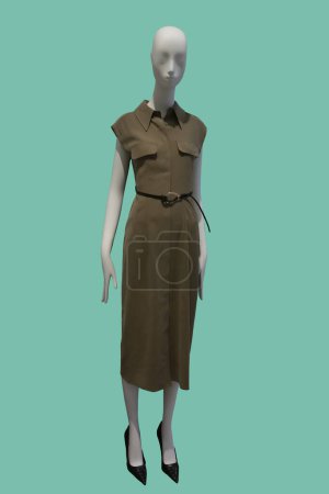 Full length image of a female display mannequin wearing brown sleeveless dress with belt isolated on green background