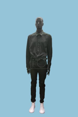 Full length image of a male display mannequin wearing gray long-sleeved shirt and trousers isolated on a blue background