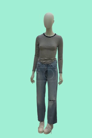 Full length image of a female display mannequin wearing striped shirt and ripped blue jeans, isolated on green background