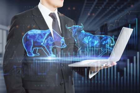 Stock exchange trading concept. The bulls and bears struggle. Equity market illustration. Close up of hand holding tablet with creative hologram and graph on blurry office interior background. Double exposure