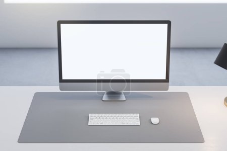 Close up of office table with empty white computer monitor and mock up place for your advertisement, lamp and keyboard on blurry background. 3D Rendering