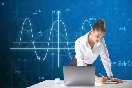Attractive young european businesswoman leaning on desktop with laptop and writing abstract glowing mathematical formula graph on blue background. Equation, digital data and mathematics app concept