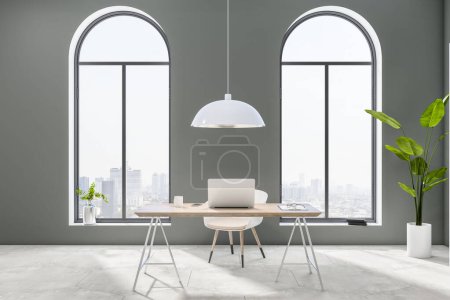 Frontansicht auf stilvollem hellen Arbeitstisch mit Laptop im sonnendurchfluteten Home Office mit Blick auf die Stadt aus Bogenfenstern und Betonboden. 3D-Rendering