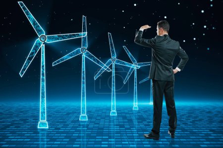 Photo for Young businessman looking at glowing digital wind mill turbine hologram on blue background. Wind generator concept - Royalty Free Image