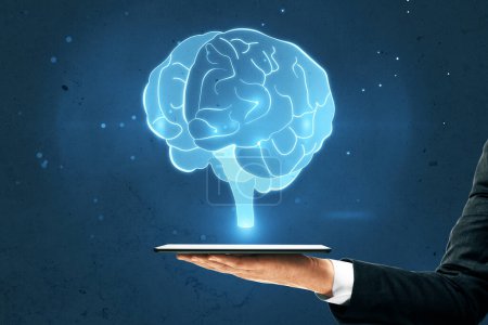 Close up of businessman hand holding tablet with glowing human brain hologram on blurry wall background. Neurology research and artificial intelligence concept