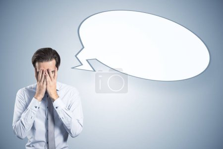 Photo for Anxious young man with empty speech bubble on gray background. Opinion and mock up place - Royalty Free Image