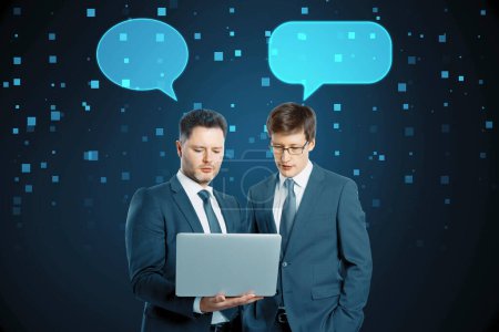 Businessmen with speech bubbles using laptop together on blurry squares blue background. Technology, metaverse, teamwork and success concept