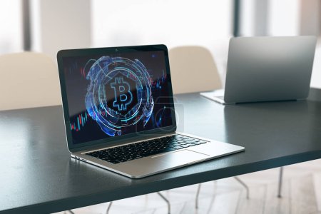 Close up of laptop computer on desktop with glowing bitcoin hologram on blurry background. Money, digital banking and cryptocurrency concept. 3D Rendering