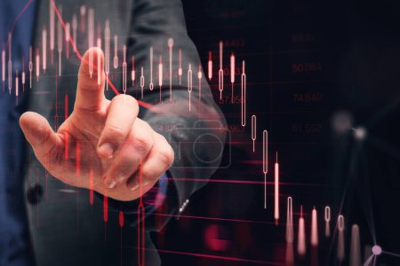 Close up of businessman hand pointing at downward red candlestick chart on dark background. Financial crisis and recession concept. Double exposure