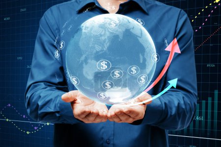 Close up of businessman hands holding glowing globe, financial arrows and money signs on blurry background. Digital world, cryptocurrency, online banking trade and technology concept