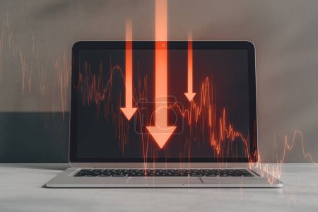 Close up of laptop on desktop with downward red business chart and arrows on blurry background. Crisis, recession and financial failure concept. Double exposure