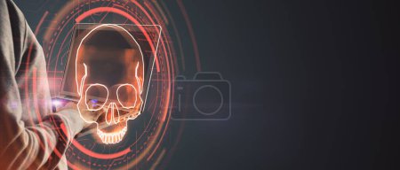 Hacker using laptop computer with digital red skull on wide dark background with mock up place. Ransomeware, virus and pirate threat concept. Double exposure