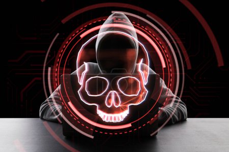 Hacker at desktop using laptop with digital red skull hologram on dark background. Ransomeware, virus and pirate threat concept. Double exposure