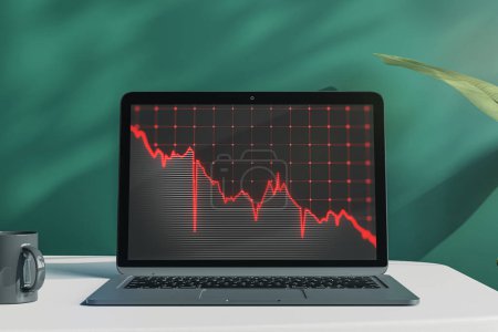Close up of laptop on desktop with coffee cup, falling red business graph grid on chalkboard background. Crisis, recession and stock market concept. 3D Rendering