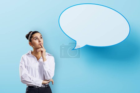 Photo for Attractive pensive european businesswoman with speech bubble on blue background. Opinion, speech and communication concept. Mock up place - Royalty Free Image