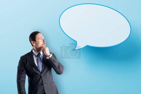 Photo for Attractive young european businessman with speech bubble on blue background. Opinion, speech and communication concept. Mock up place - Royalty Free Image