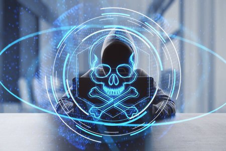 Piratage et piratage en ligne concept créatif avec une personne en sweat à capuche sans visage travaillant avec un ordinateur portable sur fond de bureau sombre et crâne bleu et os hologramme numérique, double exposition