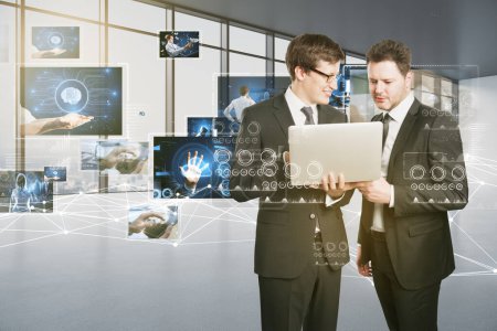 Connecting businesspeople, video conference concept. Attractive european businessmen using laptop with polygonal mesh and images on blurry office interior background