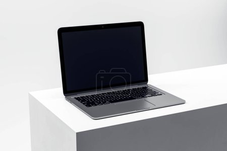 Ordinateur portable contemporain présentant un écran blanc sur un podium élégant, parfait pour les visuels de marketing numérique. Expéditeur 3D