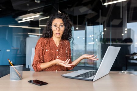 Frustrated and sad woman inside office looking at camera, businesswoman unhappy with achievement results working at desk using laptop at work.