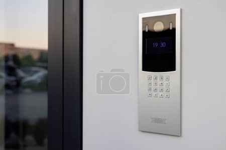 Timbre con cámara de video y micrófono, en la pared blanca de un edificio de apartamentos, cámara del timbre.