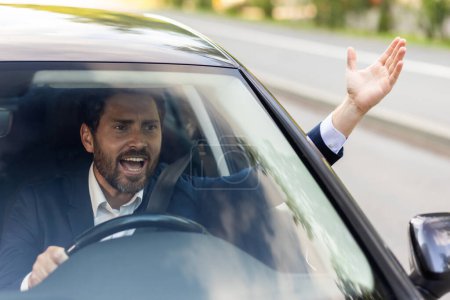 Téléchargez les photos : Photo en gros plan d'un jeune homme d'affaires en colère conduisant une voiture, criant et agitant les mains. - en image libre de droit