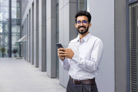 Ein professionell gekleideter Mann konzentriert sich auf das SMS-Schreiben auf seinem Smartphone, während er in einer modernen städtischen Umgebung steht und Technologie und Geschäftsleben präsentiert.