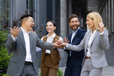 Photo for A diverse group of happy business professionals celebrate victory with a high five in an urban setting. - Royalty Free Image