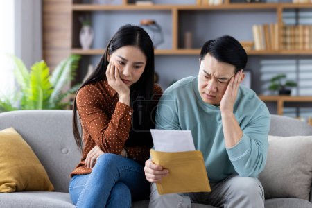 Un homme et une femme assis sur un canapé examinant des documents avec une expression inquiétante, décrivant des questions financières ou domestiques.