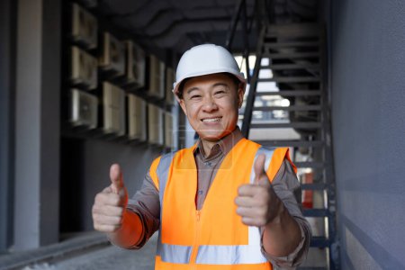 Confident construction worker in safety vest gives a thumbs up at a building site, signaling project success.