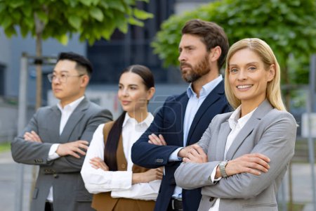 Téléchargez les photos : Un groupe de quatre professionnels du monde des affaires se tenant debout devant un immeuble de bureaux, dépeignant le travail d'équipe et le leadership. - en image libre de droit
