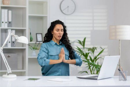 Une femme dans un état calme de méditation sur son lieu de travail, cherchant la pleine conscience au milieu de son environnement de travail occupé.