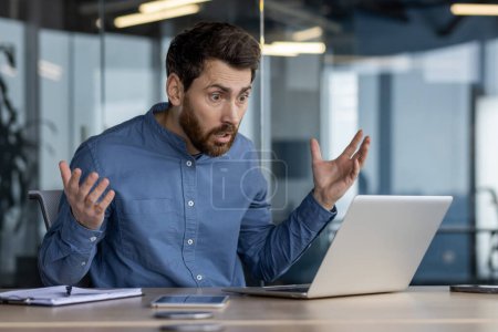 Aufnahme eines erschrockenen Mannes in einem Büro, der schockiert auf etwas auf seinem Laptop-Bildschirm reagiert. Erfasst das Konzept unerwarteter Nachrichten oder Fehler.