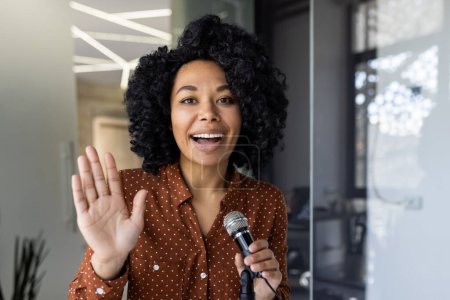 Eine fröhliche afroamerikanische Geschäftsfrau moderiert einen Podcast, spricht mit einem strahlenden Lächeln in ein Mikrofon und vermittelt Begeisterung und Professionalität.