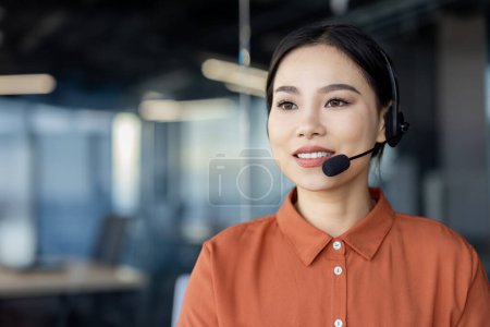 Selbstbewusste Geschäftsfrau, die während ihrer Arbeit in modernen Büroräumen ein Headset trägt und Professionalität und Erreichbarkeit zeigt.