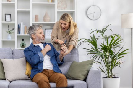 Mujer y hombre teniendo una conversación intensa después de ver un mensaje en un teléfono inteligente mientras están sentados en un sofá.