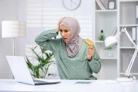 Deceived woman in hijab trying to make an online purchase, business woman holding bank credit card, rejected money transfer error, fraudulent actions.