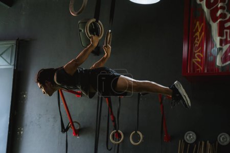 Foto de Hombre en el gimnasio colgando en los aros - Imagen libre de derechos
