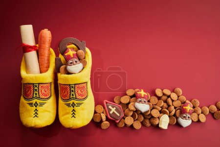 San Nicolás - Día de las Sinterklaas con zapatos, zanahorias y dulces tradicionales sobre fondo rojo.