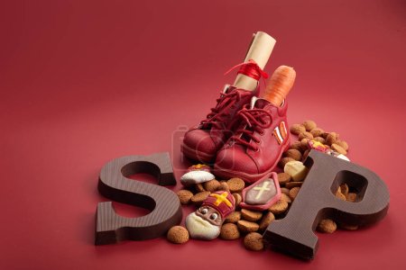 Saint Nicholas - Sinterklaas day with shoe, carrot and traditional sweets on red background.