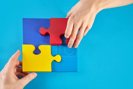 Foto de Father and autistic son hands holding jigsaw puzzle shape. Autism spectrum disorder family support concept. World Autism Awareness Day. - Imagen libre de derechos