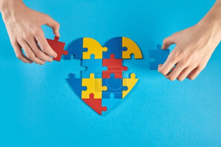 Photo for Autistic boy hands holding jigsaw puzzle heart shape. Autism spectrum disorder family support concept. World Autism Awareness Day. - Royalty Free Image