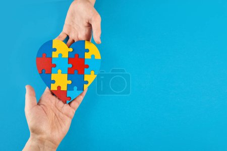 Photo for Father and autistic son hands holding jigsaw puzzle heart shape. Autism spectrum disorder family support concept. World Autism Awareness Day. - Royalty Free Image