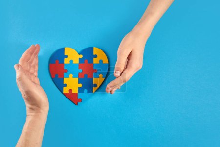 Photo for Father and autistic son hands holding jigsaw puzzle heart shape. Autism spectrum disorder family support concept. World Autism Awareness Day. - Royalty Free Image