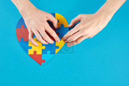 Photo for Autistic boy hands holding jigsaw puzzle heart shape. Autism spectrum disorder family support concept. World Autism Awareness Day. - Royalty Free Image