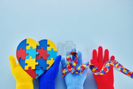 Mains tenant un ruban puzzle pour la Journée mondiale de sensibilisation à l'autisme
