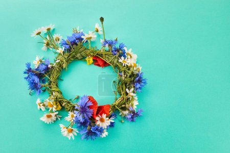 Wreath of chamomile flower on green background. Midsummer holiday background.