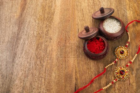 Raksha Bandhan background with Rakhi string, Rice Grains and Kumkum.