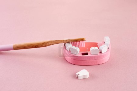 Téléchargez les photos : Journée nationale des brosses. Dent avec brosse à dents sur fond rose. Concept de santé dentaire - en image libre de droit